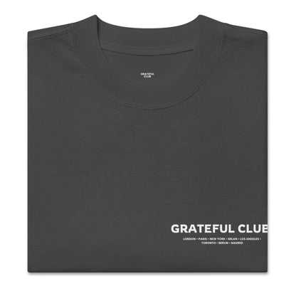 Folded black t-shirt with 'Grateful Club' text on a white background